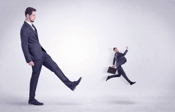 istock Big man kicking little himself out 868611384