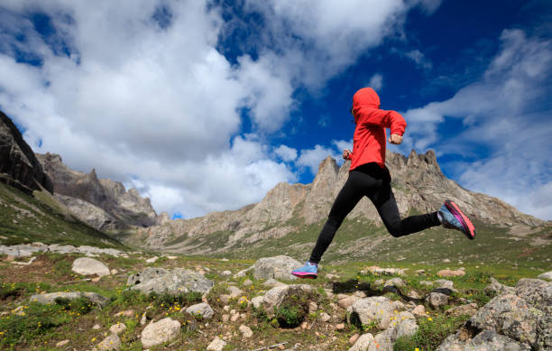 istock young woman trail runner jumping over stream water at mountain 868614620