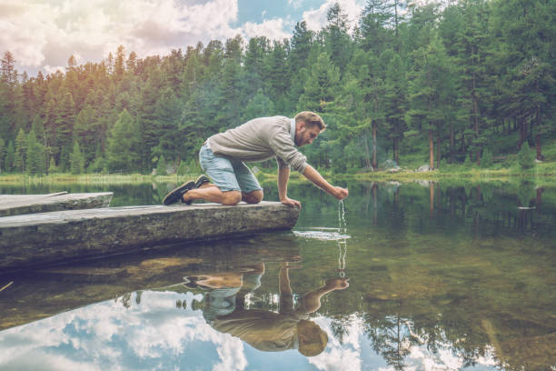 istock Young man playing with water from mountain lake 868620172