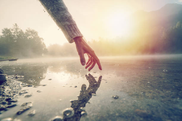 finger touches surface of mountain lake, switzerland - clear thinking imagens e fotografias de stock