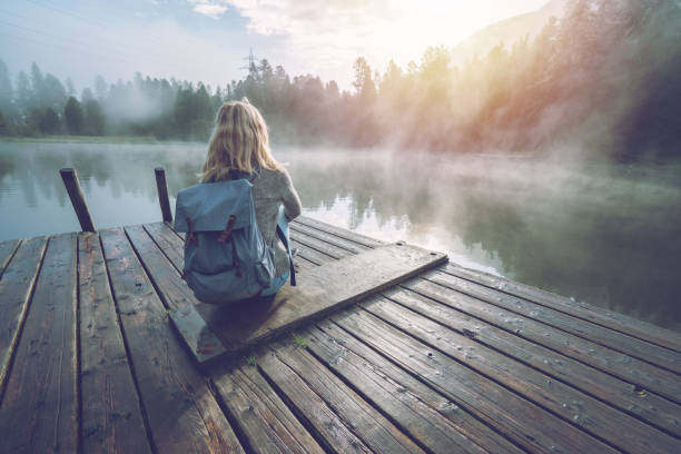 ragazza di montagna che si gode la nebbia mattutina dal molo del lago, il sole che sorge - switzerland mountain range engadine lake foto e immagini stock