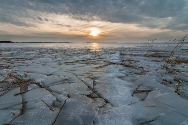istock Mystical evening winter-spring landscape. A dramatic sunset over a large frozen lake. Coastal reeds under an interesting ice crust. First thaw 868630714