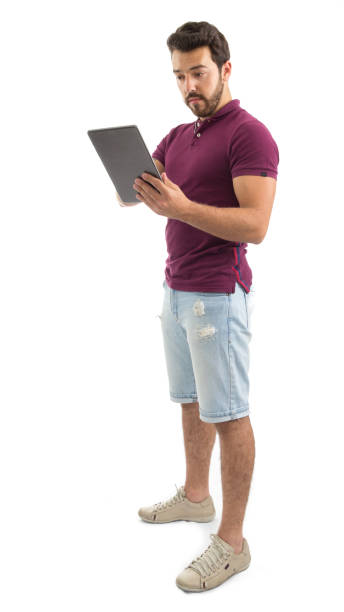 retrato de cuerpo entero de hombre amable. tableta digital. él lleva una camisa de polo de magenta y shorts jeans". n - jean shorts fotografías e imágenes de stock