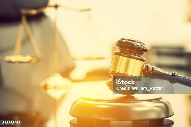 Legal Office Of Lawyers Justice And Law Concept Wooden Judge Gavel Or A Wood Hammer And A Soundboard Used By A Judge Person On A Desk In A Courtroom With A Blurred Brass Scale Of Justice Behind Stock Photo - Download Image Now