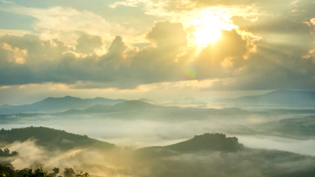 Time-lapse fog above mountain and sunlight through clouds at sunrise in Thailand