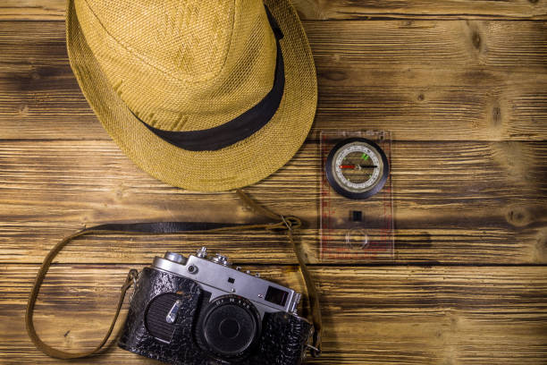 istock Compass, hat and retro photo camera on wooden background 868658362