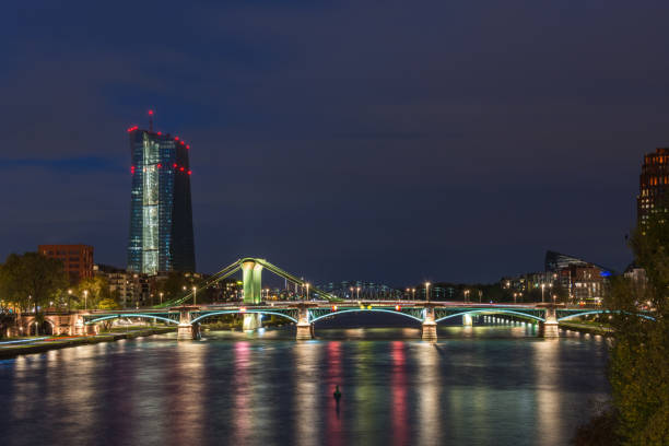 istock The EZB building in Frankfurt with red lights during blue hour with a lit bridge in front 868659864