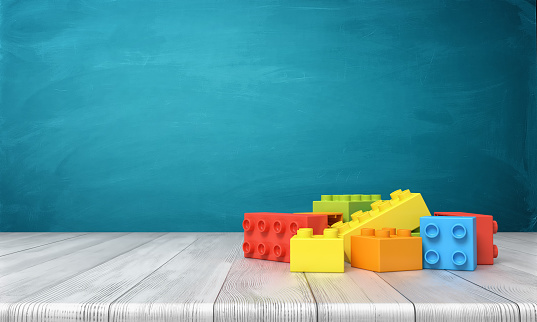 3d rendering of a toy building blocks lying in a colorful pile over a wooden desk on a blue background. Play time. Construction blocks. Toys and games.