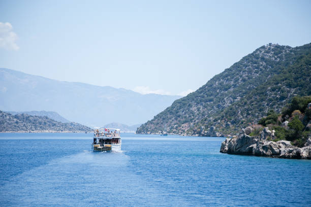 UCHAGIZ SIMENA, TURKEY - MAY 20: bay of Uchagiz village in Antalya province of Turkey with mountains covered by evergreen bushes shut on sunny day with one turistic boat with Turkish flag in 2016