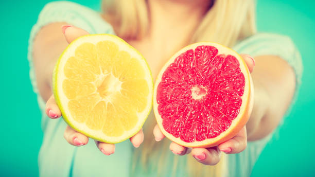 istock Halfs of yellow red grapefruit citrus fruit in human hands 868670200
