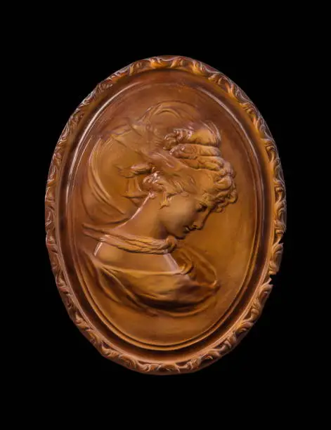 Photo of bronze woman's face in a medallion on a black background