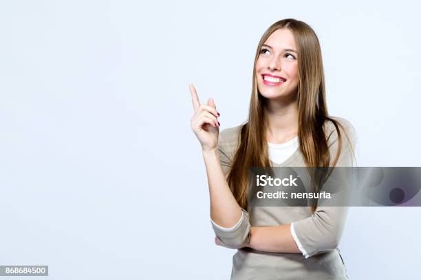 Hermosa Joven Apuntando Hacia Arriba Sobre Fondo Blanco Foto de stock y más banco de imágenes de Indicar