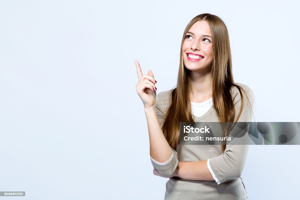 Belle jeune femme pointant vers le haut sur fond blanc. - Photo de Montrer du doigt libre de droits