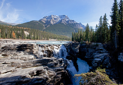 water rushes over the rocks with mountain behind in jasper, alberta