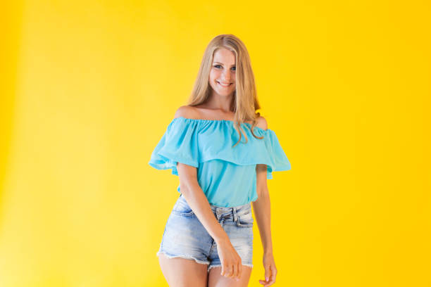 istock beautiful blonde with blue shorts on a yellow background 868695290