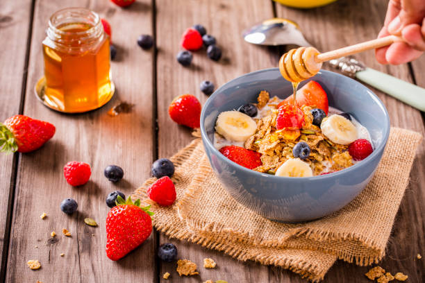 istock honey and fruit cereal with a hand swirling honey 868696168