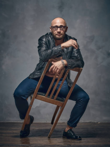 istock A brutal bald guy sits on a wooden chair. 868702186