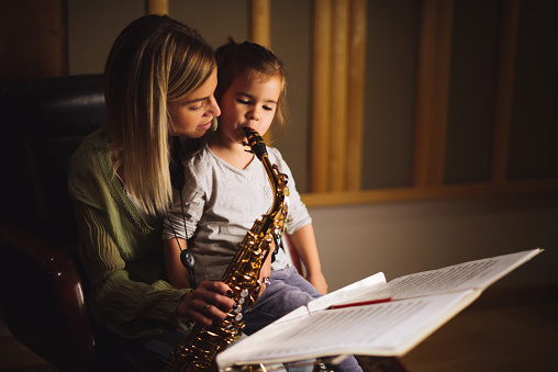 Mother and daughter playing saxophone in a music studio.