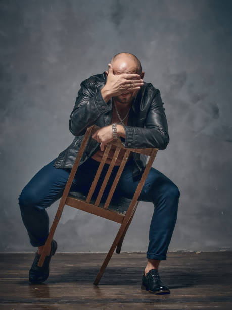 istock A brutal bald guy sits on a wooden chair. 868702562