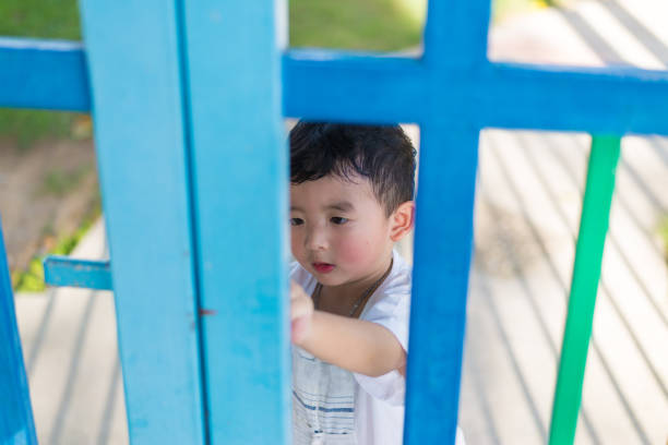 istock Sad Asian kid behind the grid trying to escape. shallow DOF 868702942