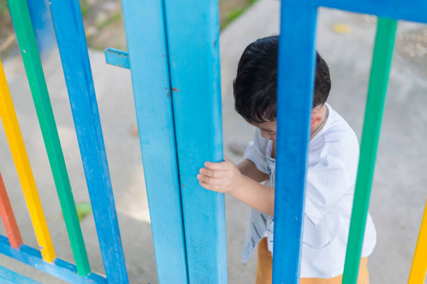 istock Sad Asian kid behind the grid trying to escape. shallow DOF 868702958