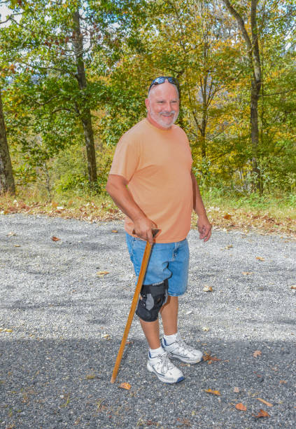 Man with cane Senior man with a cane on a road knee brace stock pictures, royalty-free photos & images