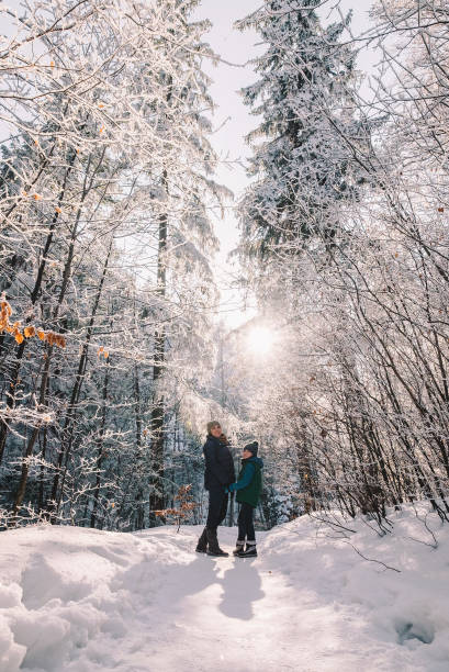 Mother with son walk together in winter forest