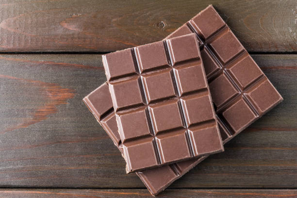istock Bitter, dark chocolate bar on wooden planks background, top view 868713762