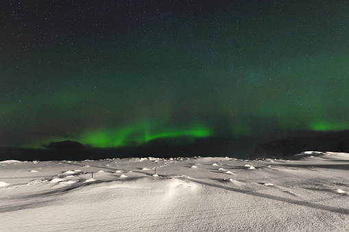 Green lights-aurora borealis illuminate from the N.the Sandelva river plain and beach at Yttresand village on Sandbotnen bay-N.Flakstadoya island on a cold quiet night. Lofoten-Nordland fylke-Norway.