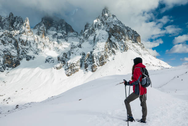Young woman explorer looking at the mountain range in winter scenery stock photo