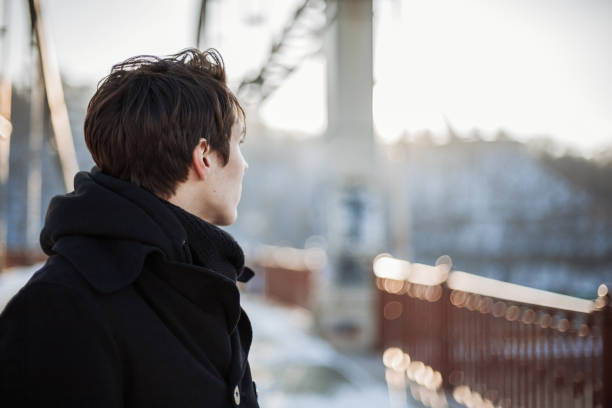 jonge man staande op de brug - alleen één tienerjongen stockfoto's en -beelden