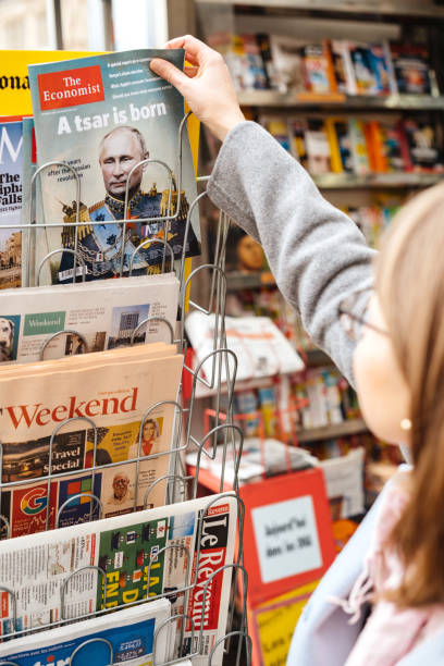 Strasbourg: Woman buying The Economist magazine at press kiosk featuring Vladimir Putin on cover and headline A Tsar is Born