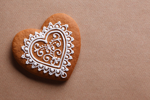 Decorative heart cookie on textured paper background.