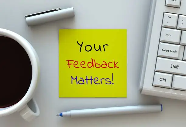 Photo of Your Feedback Matters, message on note paper, computer and coffee on table