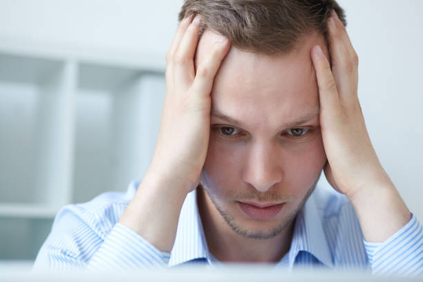 istock Feeling tired. Tired man being overloaded at work with many tasks. Businessman being depressed by working in office. Frustrated young handsome man looking exhausted while sitting at his working place. 868751964