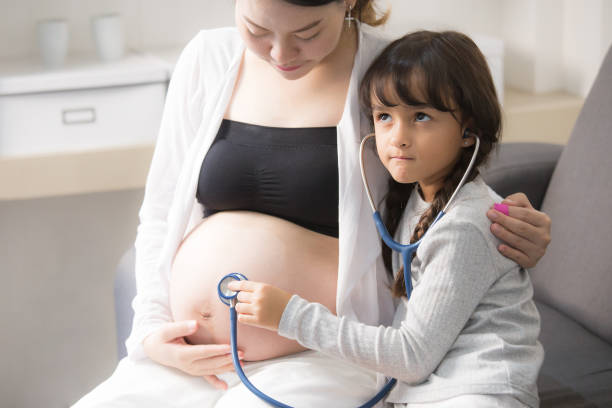 istock Little cute girl using stethoscope check stomach to her mother. 868752502