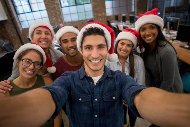 люди в офисе делают селфи, празднуя рождество - santa hat фотографии стоковые фото и изображения