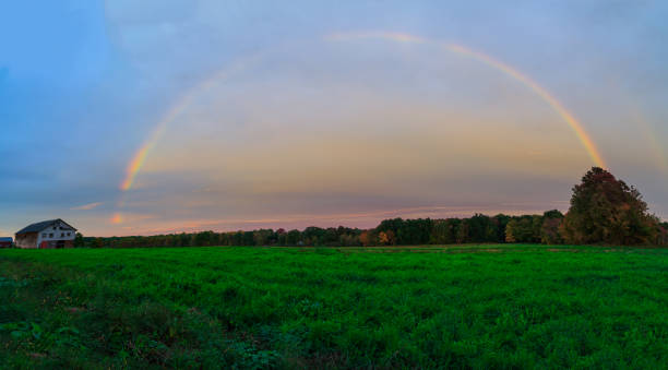 Rainbow over Berkshires and Hudson Valley NY during fall time and rain storm. Sky gray and blue. Leaves orange and yellow.