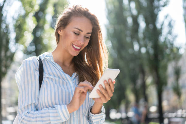 istock Beautiful woman using app on her cell phone outdoors 868762088