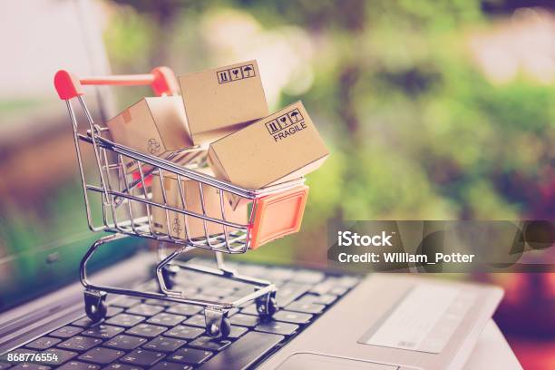 Concetto Di Servizio Di Shopping E Consegna Online Cartoni Di Carta In Un Carrello Della Spesa Su Una Tastiera Per Laptop Questa Immagine Implica Lo Shopping Online Che I Clienti Ordinano Cose Dai Siti Del Rivenditore Via Internet - Fotografie stock e altre immagini di Shopping online