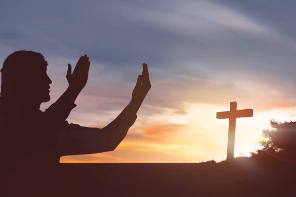 istock Silhouette man raising hand while praying to jesus 868776718