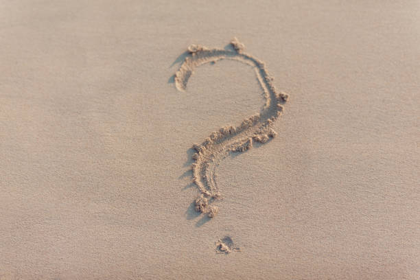 istock Question mark drawn on the sand of a beach in summer. 868804672