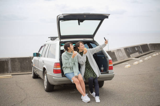 eles levam um almoço sanduíche no estacionamento em frente à praia. . - beach parking lot car equipment - fotografias e filmes do acervo