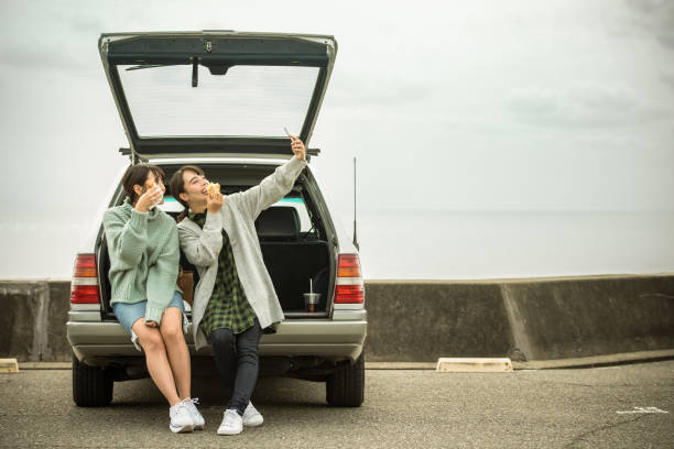 eles levam um almoço sanduíche no estacionamento em frente à praia. . - beach parking lot car equipment - fotografias e filmes do acervo