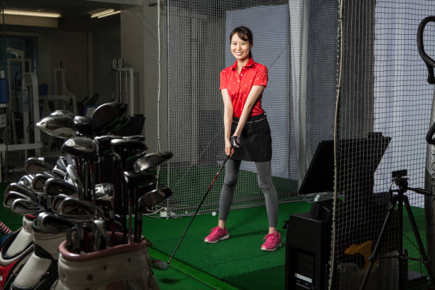 una donna con un sorriso in uno studio di golf. - simulatore foto e immagini stock