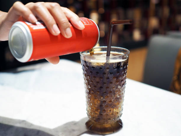 Pouring cola over ice cube in clear glass with straw. Pouring cola over ice cube in clear glass with straw. Selective focus quench your thirst pictures stock pictures, royalty-free photos & images