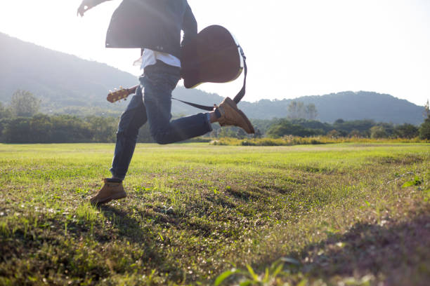 young enthusiastic man carrying his guitar running
