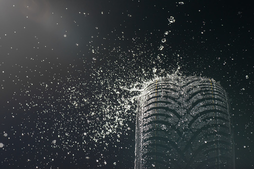 High-speed photography of a new, high performance wet tire. Water splash on the left side. Copy space available.