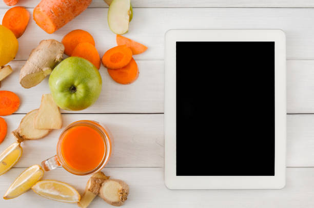 istock Detox carrot smoothie ingredients, top view on white with tablet screen 868850218