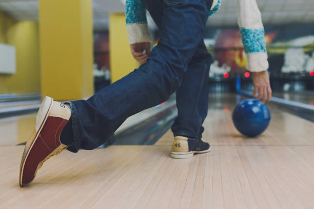 istock Man throw ball at bowling lane, cropped image 868853842